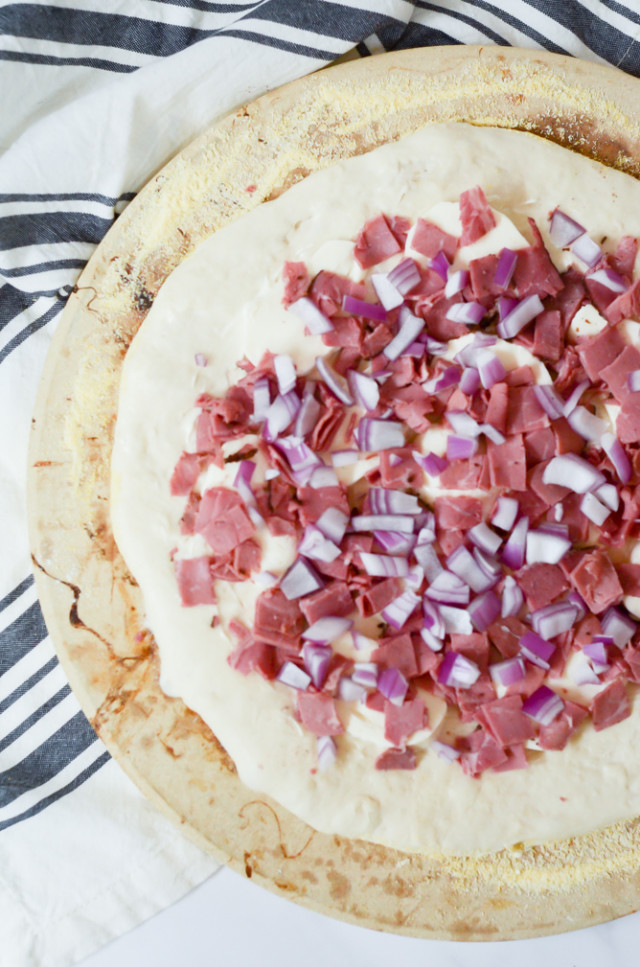 Pastrami Pizza starts with mayonnaise, mozzarella, pastrami and red onion before baking.