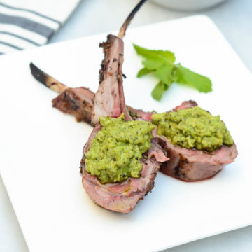 Lollipops of Herb Crusted Rack of Lamb are graced with a hearty dollop of Mint Pea Pesto.