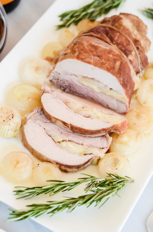 Juicy slices of Pear and Gruyere Stuffed Pork Tenderloin with Roasted Cippolini Onions. 