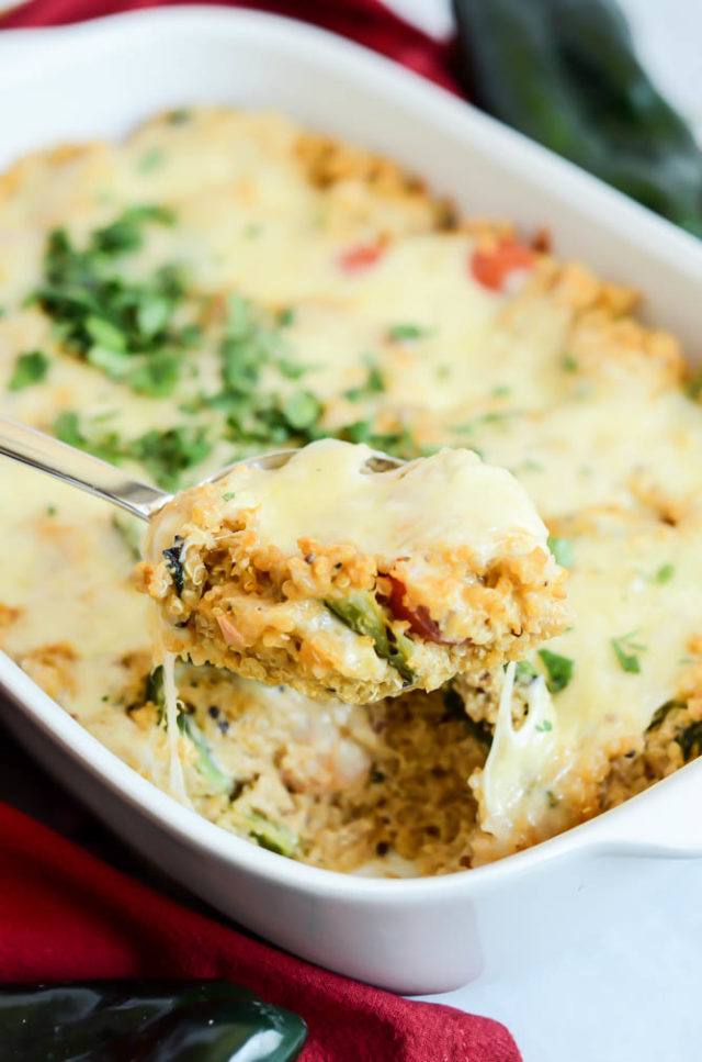 A spoonful of finished Shrimp and Poblano Enchilada Bake held up over the finished dish.