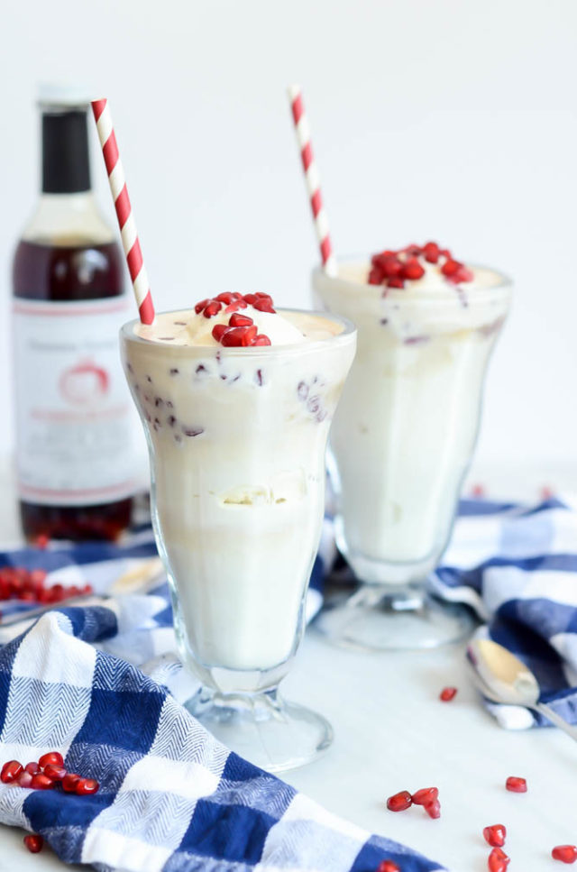 Two frosty pomegranate soda ice cream floats garnished with pomegranate seeds.