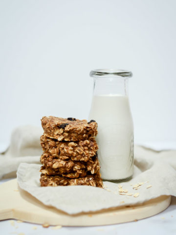 Four Peanut Butter Banana Breakfast Cookies stacked alongside a carafe of milk.