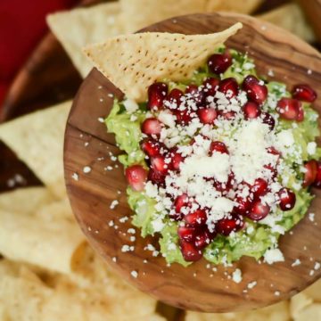 An overhead shot of Festive Guacamole in a bed of tortilla chips.