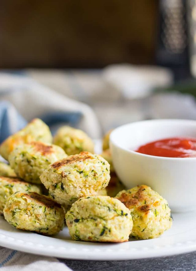 A plate of Cheesy Zucchini Tots with a side of dipping sauce is the perfect toddler-friendly finger food snack!