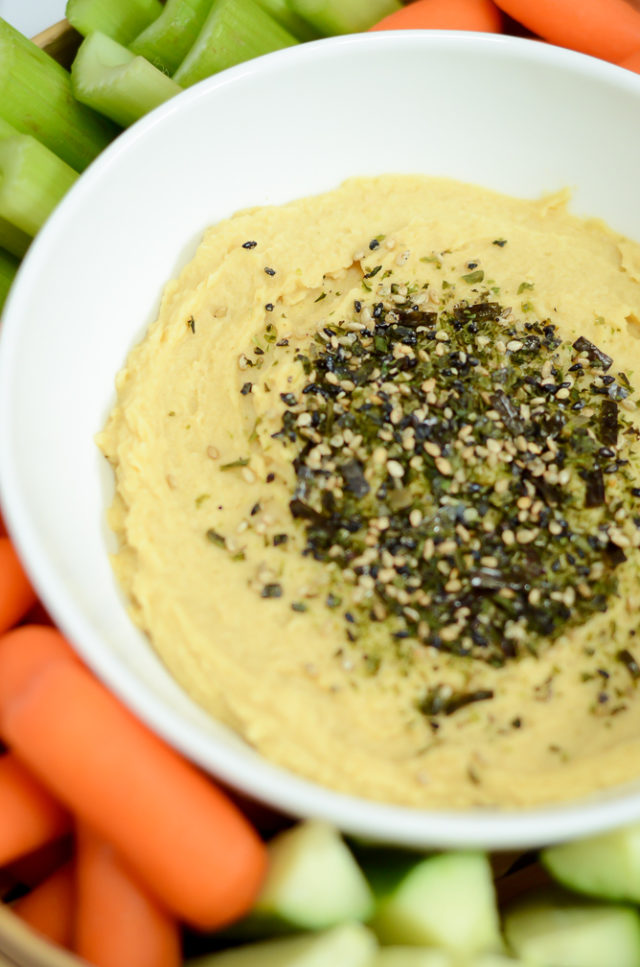 A close-up shot of Miso Furikake Hummus surrounded by fresh vegetables.