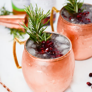 A frosty Pomegranate Mule garnished with fresh pomegranate seeds and rosemary sprigs.