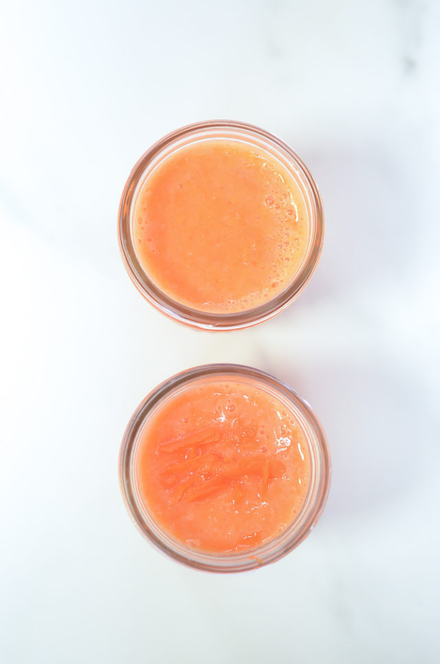 An overhead shot of two orange-carrot smoothies in Mason jars.