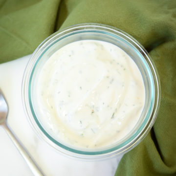 A dish of homemade tzatziki with a spoon sitting next to it.