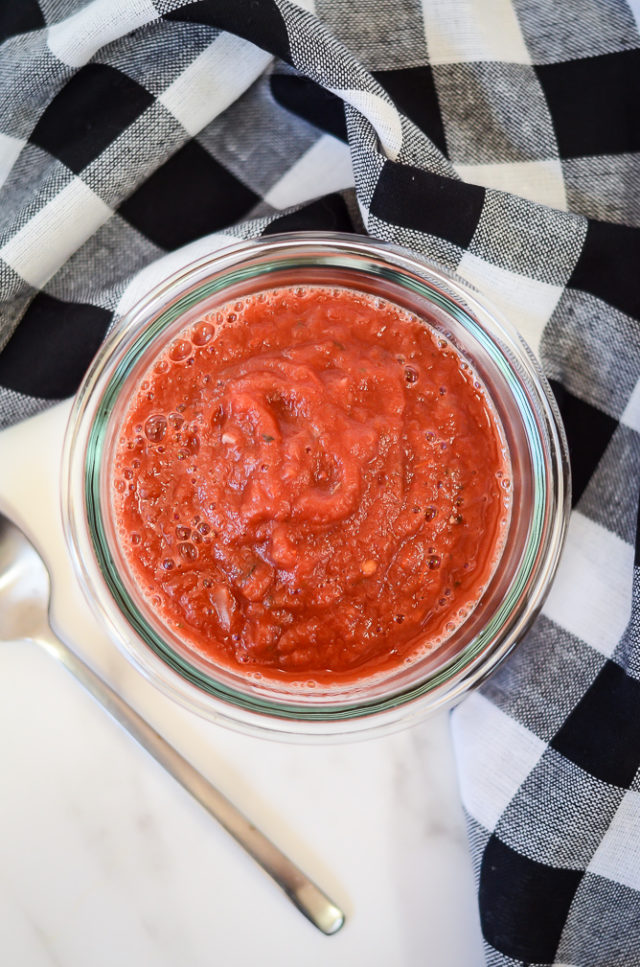 A jar of homemade marinara sauce with a spoon next to it.
