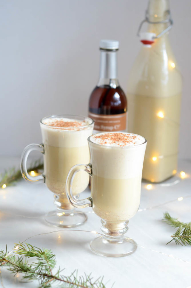 Two glasses of Winter Spiced Vanilla Eggnog amid twinkly lights.