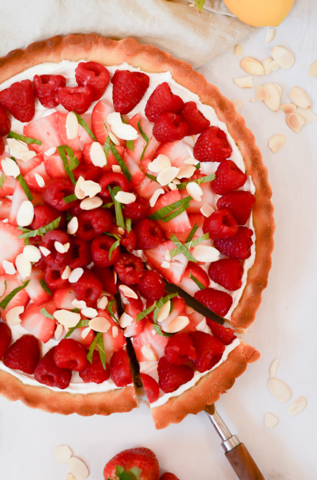 An overhead shot of a loaded Greek Yogurt Berry Tart with Almond Crust, with a piece being pulled out of it.