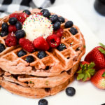 A plate of funfetti waffles topped with butter, sprinkles and fresh berries.