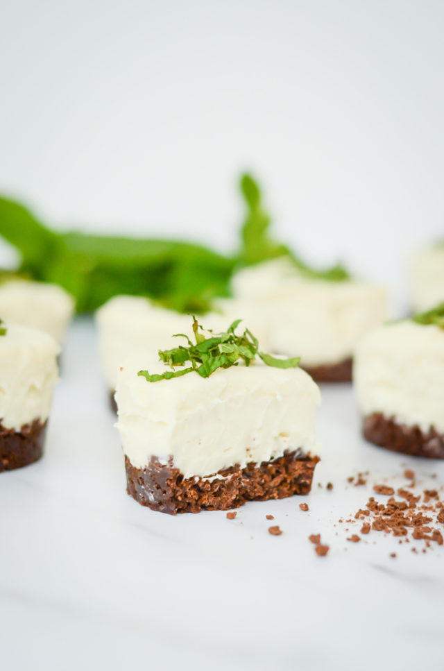 A fresh mint mini cheesecake with a bite out of it with more mini cheesecakes behind it.