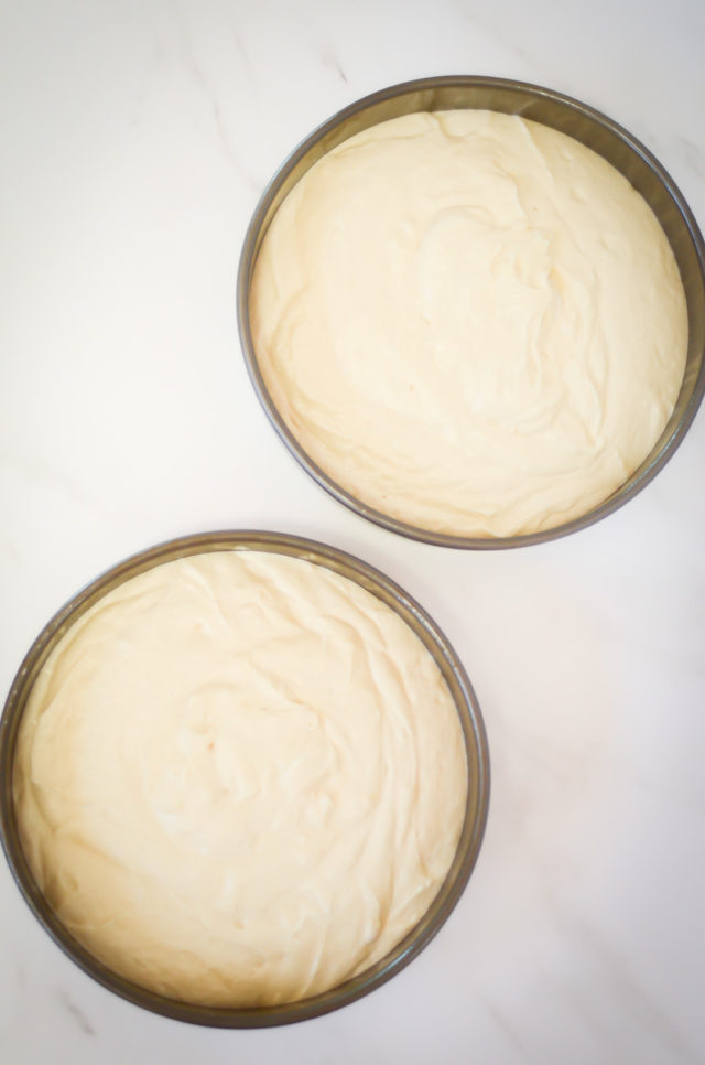 Vanilla cake batter evenly divided into two prepared cake pans.