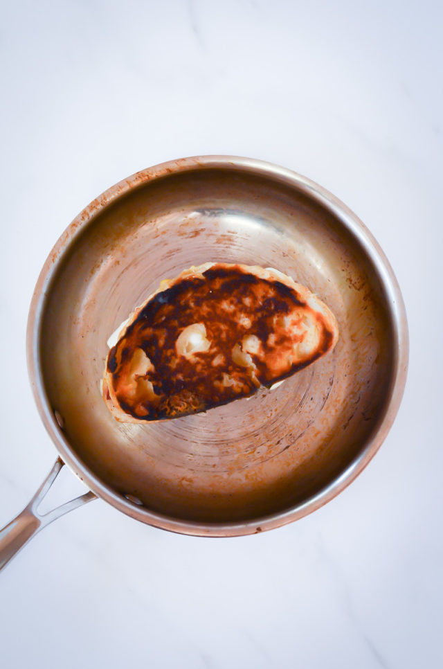 A grilled cheese cooking on a skillet.