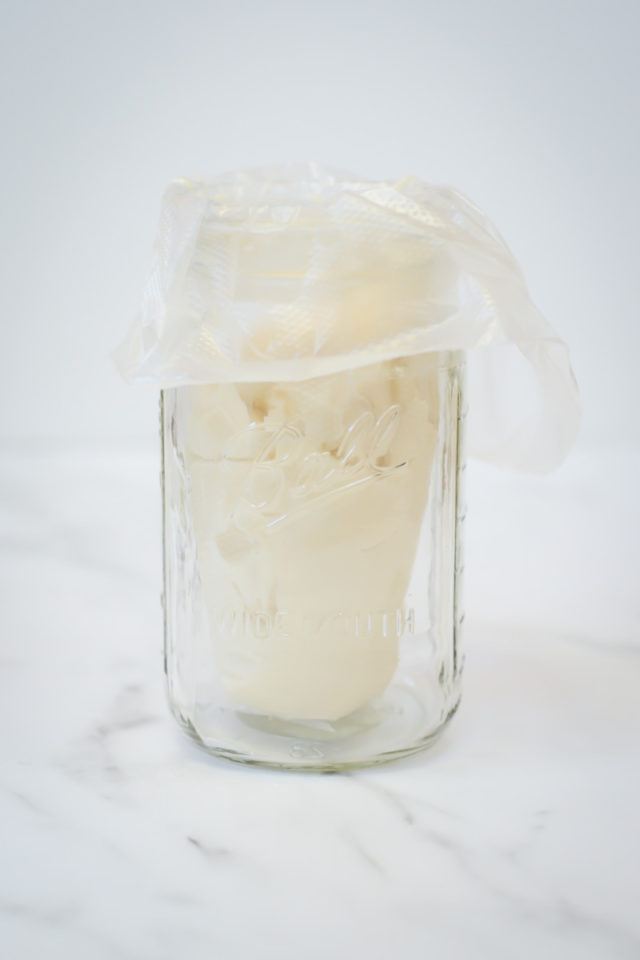 A piping bag filled with peppermint cream in a Mason jar.