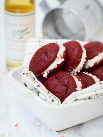 A dish full of red velvet whoopie pies with peppermint cream.