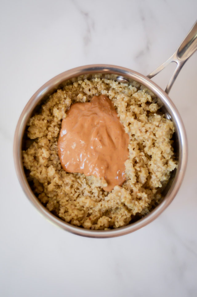 A saucepan of cooked quinoa topped with peanut butter.