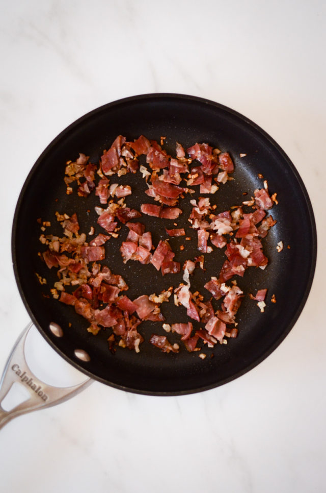 Shallots and prosciutto in a frying pan.