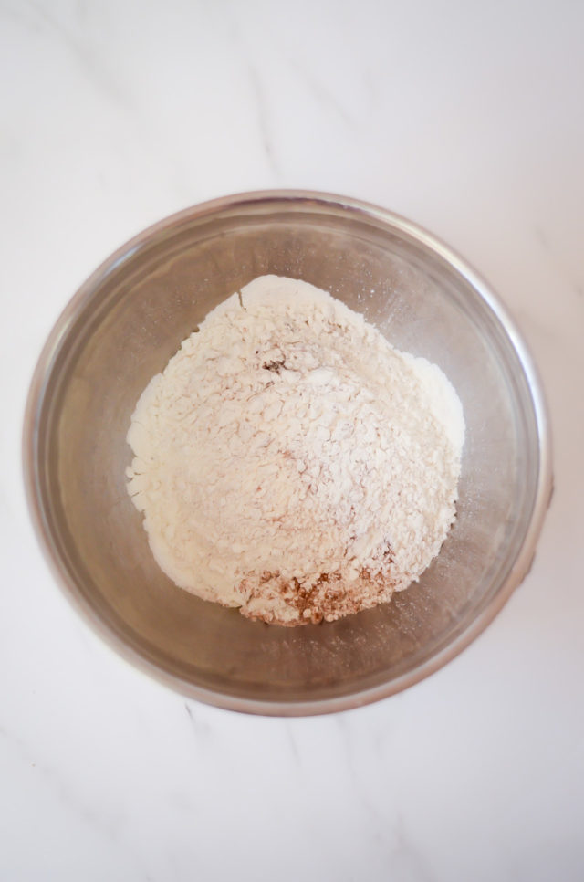 An overhead shot of a mixing bowl of dry ingredients for hot cross buns.